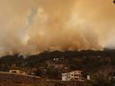 A picture taken on July 15, 2023 on the Spanish Canary Island of La Palma shows the evacuated town of Tijarafe surrounded by smoke billowing from wild fire near La Caldera de Taburiente National Park. 