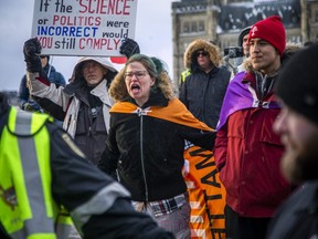 A group of people gathered for the one-year anniversary of the convoy protest on Parliament Hill and Wellington St. in Ottawa, Jan. 28, 2023.