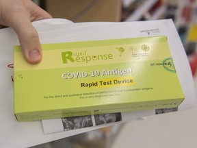 A man displays his COVID-19 rapid test kit after receiving it at a pharmacy in Montreal, Monday, Dec. 20, 2021.