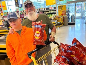 Son and father with shopping cart full of bags of ketchup chips
