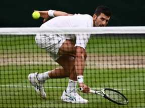 Serbia's Novak Djokovic returns the ball to Italy's Jannik Sinner during their men's singles semi-finals tennis match at the Wimbledon Championships at The All England Lawn Tennis Club in Wimbledon.