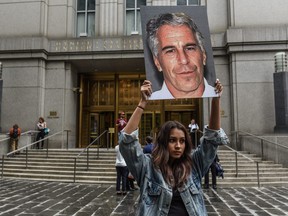 A protest group called "Hot Mess" hold up signs of Jeffrey Epstein in front of the federal courthouse on July 8, 2019 in New York City.