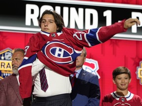 David Reinbacher puts on a Montreal Canadiens jersey after being picked by the team during the first round of the NHL hockey draft Wednesday, June 28, 2023, in Nashville, Tenn. The Canadiens signed fifth-overall draft pick Reinbacher to a three-year, entry-level contract on Wednesday.
