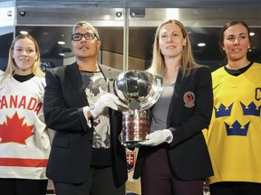 Sarah Fillier, Angela James, Jayna Hefford and Anna Kjellbin pose with the women's hockey world championship trophy.