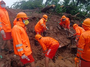 In this handout photograph released by India's National Disaster Response Force (NDRF) and taken on July 22, 2023, NDRF personnel search for victims at the site of a landslide at Irshalwadi village of Raigad district in Maharashtra state.