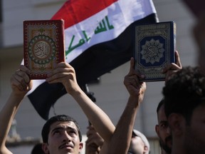 Supporters of the Shiite cleric Muqtada al-Sadr raise the Qur'an, the Muslims' holy book, during a demonstration in front of the Swedish Embassy in Baghdad