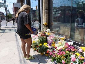 Niloo Borun adds to the growing memorial of flowers for Karolina Heubner-Makurat, 44, a married mother of  mother of two, who was shot and killed on Queen St., east of Carlaw Ave., on July 7, 2023. (Jack Boland, Toronto Sun)