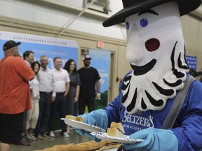 Seltzer's mascot hands out some of the 150-foot-long (45.7-meters-long) bologna sandwich that was assembled by volunteers at the Lebanon Area Fair on Tuesday, July 25, 2023 in Lebanon, Pa. Every footlong "bite" was sponsored at $100 per foot. The money was donated to Lebanon County Christian Ministries and their efforts to help people dealing with food insecurity in the Lebanon Valley.