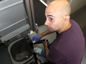 Habib Battah is seen on an Air France flight from Paris to Toronto in a June 30, 2023, handout photo, as he is cleaning blood off his pet carrier backpack that had transferred from the plane carpet from a previous passenger's hemorrhage.