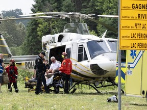 A man is transported from the police helicopter to an ambulance after he was evacuated from an isolated area in Riviere-Eternite, Que., Sunday, July 2, 2023.