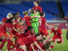Players of Canada's celebrate beating Sweden in the women's soccer match for the gold medal at the 2020 Summer Olympics in Yokohama, Japan, Friday, Aug. 6, 2021. When the Canadian women's soccer team struck gold at the Tokyo Olympics, it did so in a COVID bubble far from family and friends.