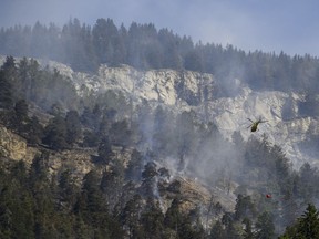 A helicopter pours water on the still burning forest