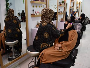 An Afghan beautician applies makeup to a client
