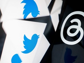 This photo illustration created in Washington, DC, on July 5, 2023, shows the Twitter logo reflected near the logo for Threads