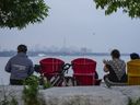 People sit along the waterfront at Humber Bay Park in Toronto on Wednesday, June 28, 2023. Toronto residents will be allowed to consume alcohol in a select number of parks across the city in the coming months after city council approved a time-limited pilot program.