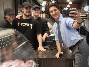 Prime Minister Justin Trudeau takes a selfie with vendors while visiting a market in St.-Hyacinthe, Que.