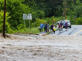 Onlookers check out a flooded road in Chester, Vermont