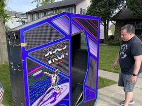 Chris Lapetino inspects the "Discs of Tron" arcade game that his brother Tim discovered on a Chicago-area sidewalk. MUST CREDIT: Tim Lapetino