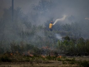 A firefighter directs water on a grass fire.