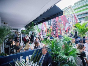 People eating at restaurant with beautiful mural in the background.