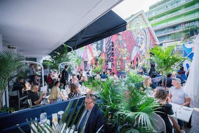 People eating at restaurant with beautiful mural in the background.