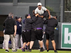 Field guards carry away one of two fans who approached Atlanta Braves right fielder Ronald Acuna Jr. as Acuna took the field for the bottom of the seventh inning of a baseball game against the Colorado Rockies, Monday, Aug. 28, 2023, in Denver.