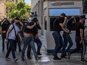 Football fans, most of them from Croatia, cover their faces while leaving the Athens Police Headquarters in Athens, on Aug. 11, 2023, as they are being detained as part of the inquiry on the death of a Greek fan during violent clashes.