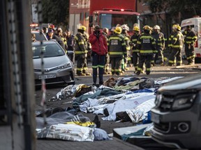 Bodies covered in blankets and sheets are seen at the scene of a fire in Johannesburg on August 31, 2023.