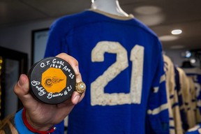 Leafs historian Mark Fera, holds a signed 1964 game-winning puck from the Buds’ Stanley Cup overtime hero, the late Bobby Baun, in Brampton, on Tuesday. Baun’s old Leafs jersey can be seen in the background. ERNEST DOROSZUK/TORONTO SUN