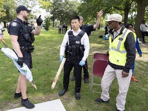 Toronto Police officers hold sharpened sticks collected as evidence at the scene of a protest that turned violent in Earlscourt Park in Toronto on Saturday, Aug. 5 2023. Toronto police say one person was stabbed and eight others were injured during a protest in the city’s west end.