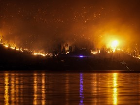 The McDougall Creek wildfire burns on the mountainside above lakefront homes, in West Kelowna, B.C., on Friday, August 18, 2023.