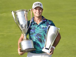 Viktor Hovland holds the Western Golf Association and the BMW Championship trophies.