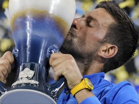 Novak Djokovic, of Serbia, kisses the Rookwood Cup as he poses for photos.