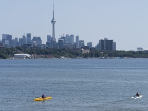 The CN Tower looms in the distance as a pair of kayakers paddle on Lake Ontario in Toronto, on Tuesday, Aug. 22, 2023.