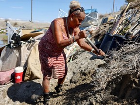 Karen Villa clears the area around her tent after Tropical Storm Hilary
