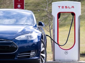 A Tesla Model S sedan is plugged into a Tesla Supercharger electrical vehicle charging station in Falls Church, Va., Feb. 13, 2023.