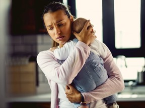 Young mother holding her baby son and consoling him at home