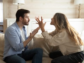 A couple are sitting on couch, arguing at home