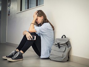Upset and depressed girl holding smartphone sitting