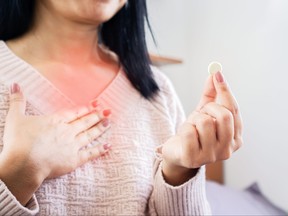 woman hand taking medicine for GERD, having problem with heartburn from acid reflux disease