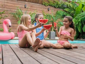 Children eating slices of summer watermelon on poolside