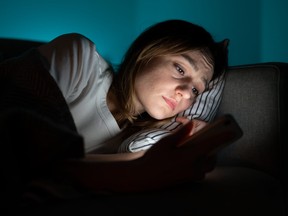 Woman Using Mobile Phone While Lying In Bed At Night, Suffering From Post-Breakup Insomnia. Anxiety.