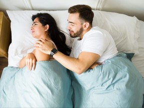 A man touches his upset partner in bed