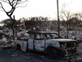 A burnt out car lies in the driveway of charred apartment complex