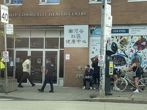 Locals and security outside the South Riverdale Community Health Centre on Queen St. East at Carlaw Ave.