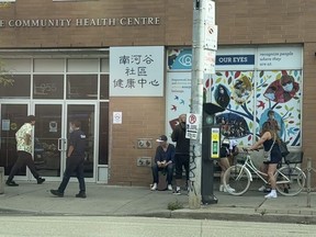 Locals and security outside the South Riverdale Community Health Centre on Queen St. East at Carlaw Ave.