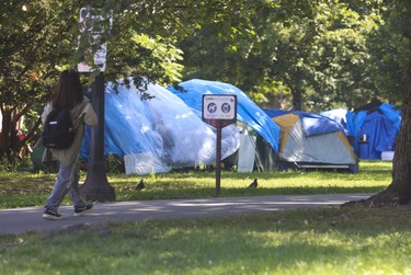 A person walks past the massive homeless encampment at Allan Gardens.