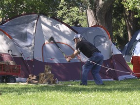 A man chops wood at the tent city located at Allan Gardens