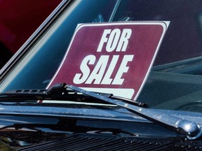 A for sale sign behind the windshield of a vehicle.