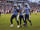 Toronto Argonauts running back AJ Ouellette (34) celebrates his touchdown against the Ottawa Redblacks with teammates wide receiver David Ungerer III (83) and wide receiver Kurleigh Gittens Jr. (19) during first half CFL football action in Toronto, on Sunday, August 13, 2023.